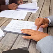 Two hands pointing at a document that is laying flat on a table.