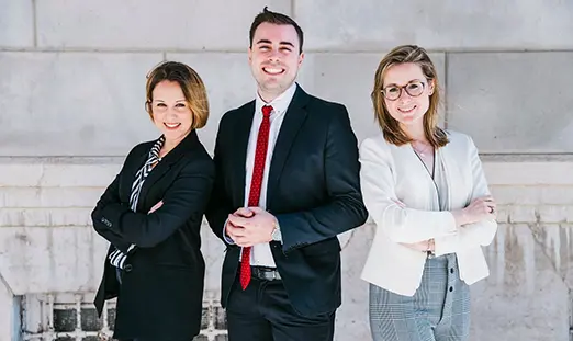 A man flanked by two ladies on each side. All with their arms crossed over their chests.